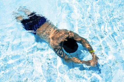 Adult male swimming underwater in an outdoor swimming pool.