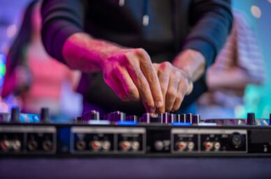 Close up of man artist DJ mixing and scratching music mixer controller.