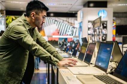 Focused ethnic man choosing laptop in shop