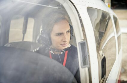 Front view from outside of a female pilot in the cockpit of an airplane.