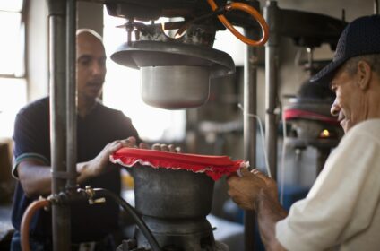 Hat makers stretching fabric on mould in workshop