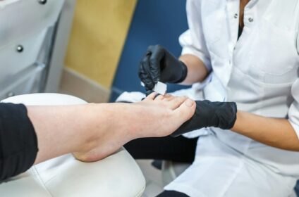 the master in black gloves in the salon makes manicure pedicure to the client